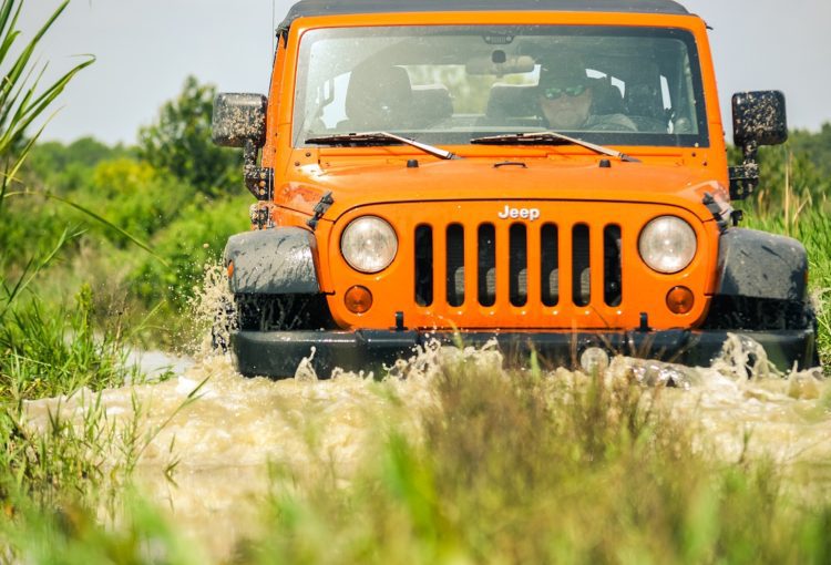 Orange Jeep Tours driving through muddy water