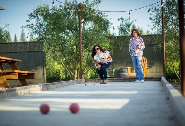Two Women Drinking Wine and Playing Bocce