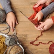 Child girl is learning to knit. Colorful wool yarns are on the wooden table. Ave Maria, Florida