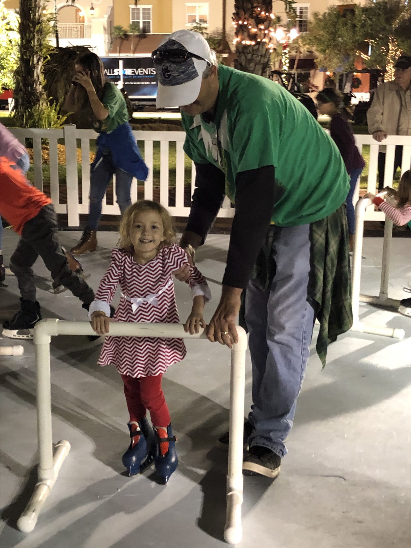 Young girl ice skating with father