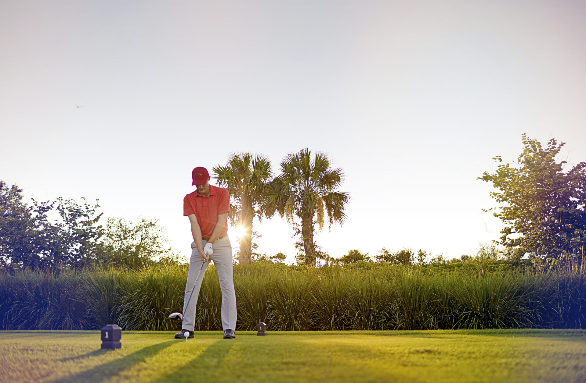 Golfer about to swing during sunset