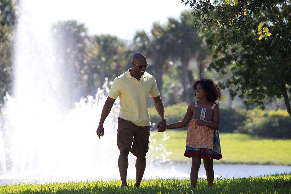 Dad and daughter holding hands in Ave Maria park