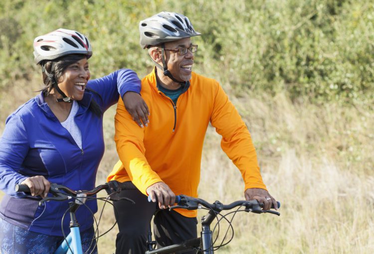 A man and a women riding bikes outside with helmets on Ave Maria, Florida