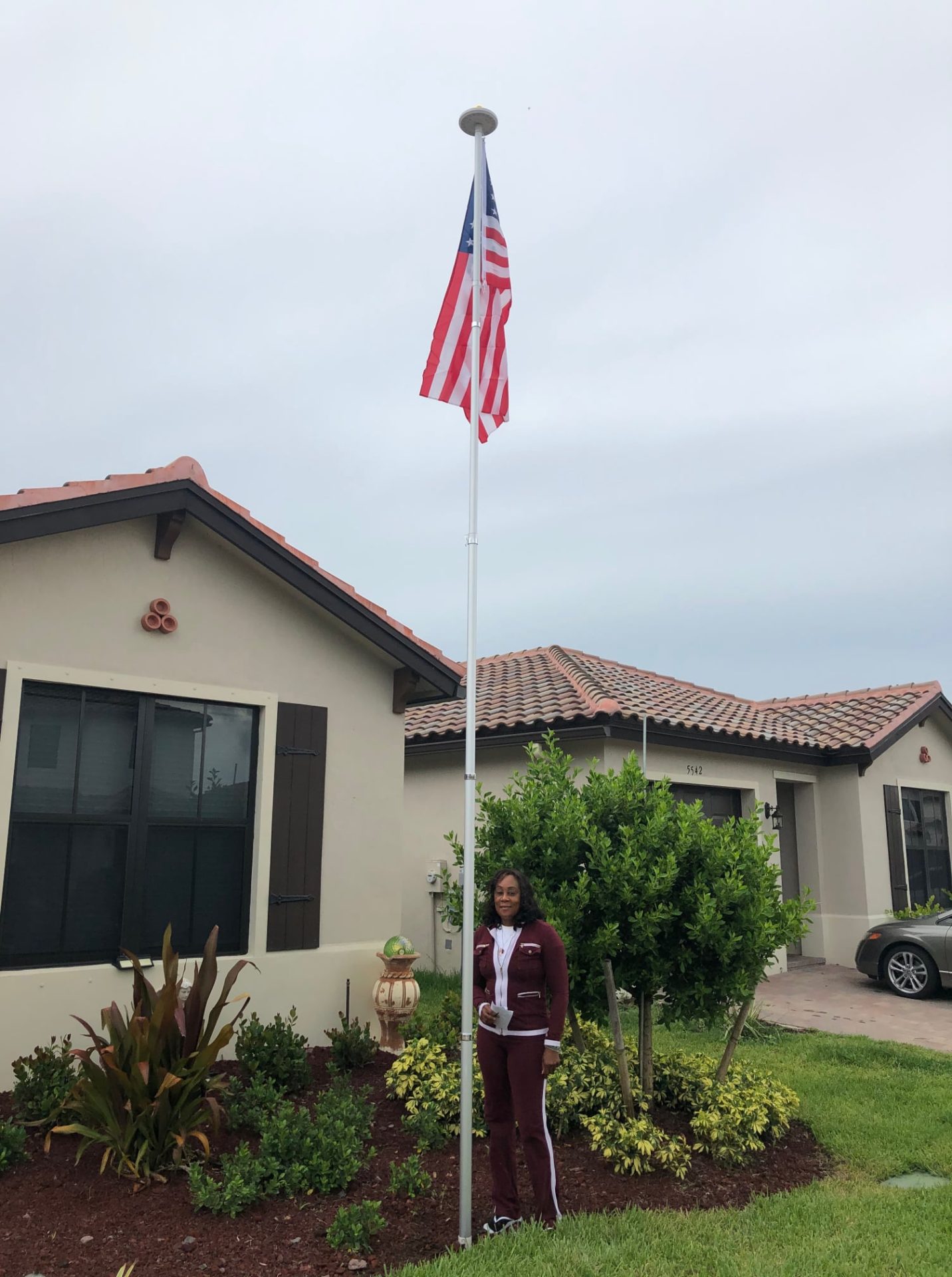 Woman standing outside home next to free-standing flagpole