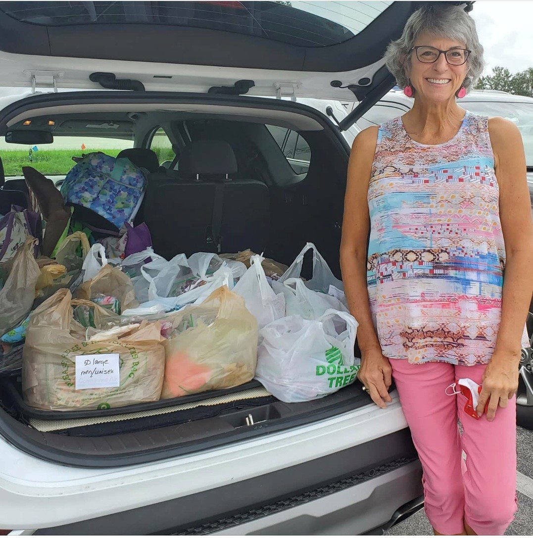 A women pictured with many bags filled with handmade masks