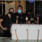 Two people with masks standing by beer cooler