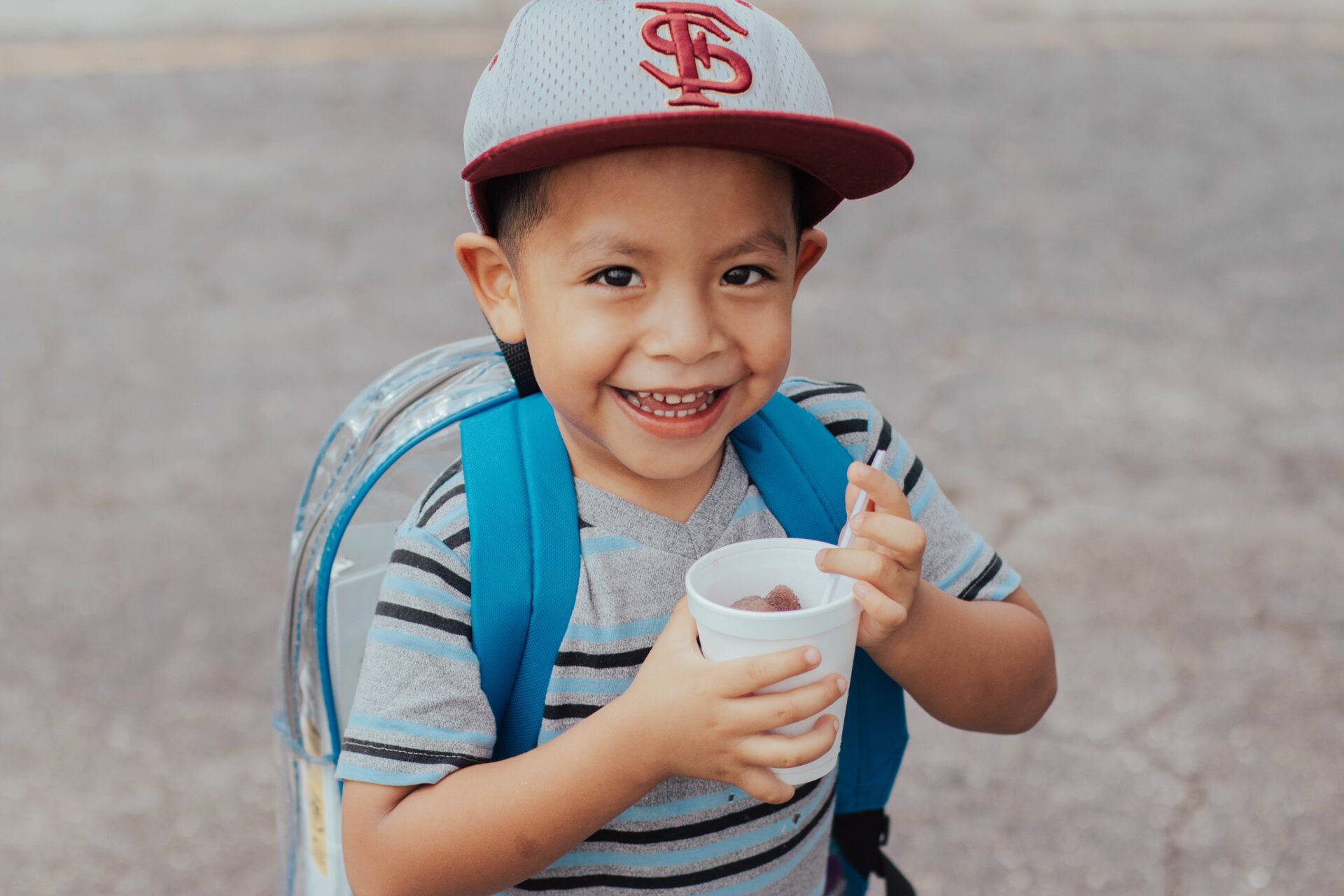 young boy smiling with cup in hand