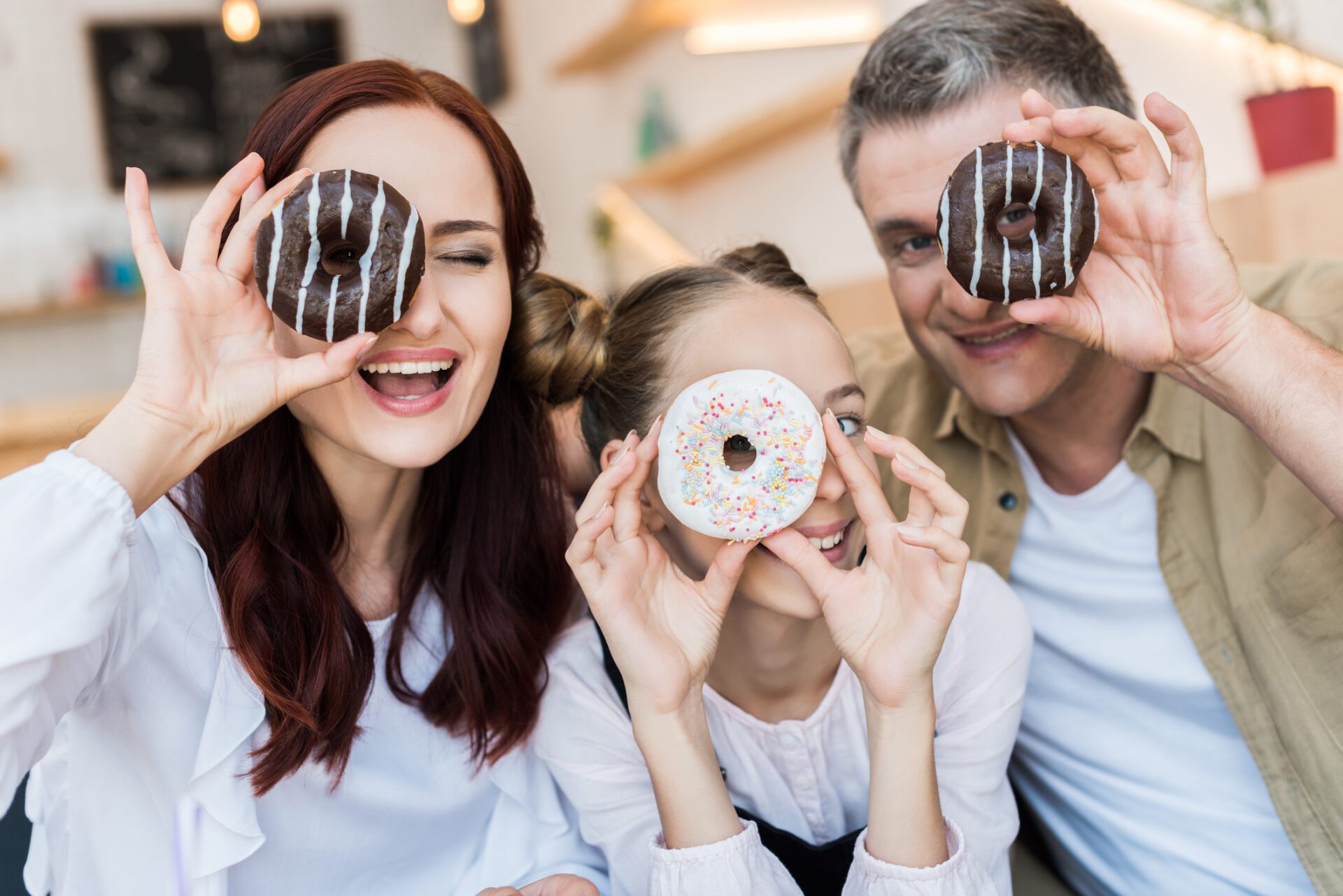 beautiful family in cafe beautiful family looking at camera through doughnuts in cafe Doughnut Stock Photo