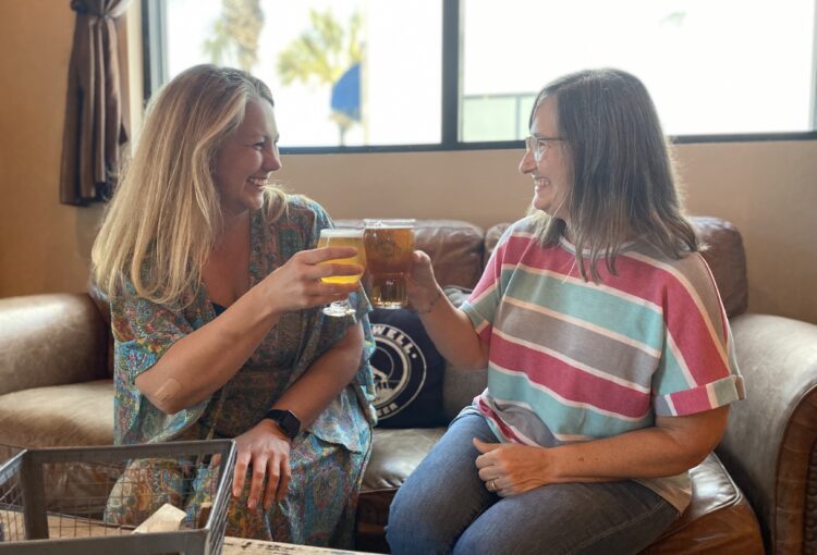 Two women cheers drinks at Oil Well Craft Beer