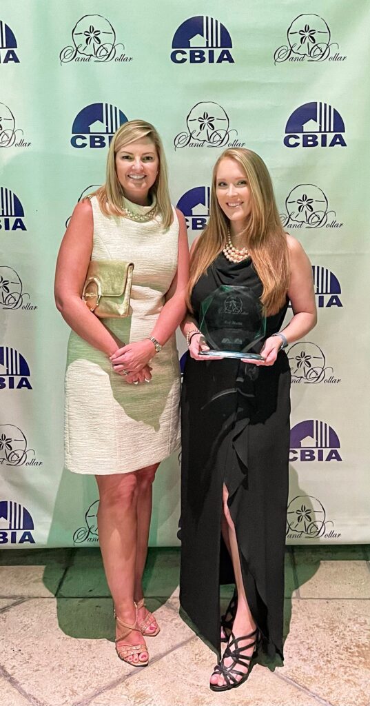 Two women smiling holding Sand Dollar Award