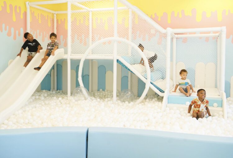 Children play in ball pit, climbing activities and slide at the soft activity playroom of Kibitz n' Play in Ave Maria, FL.