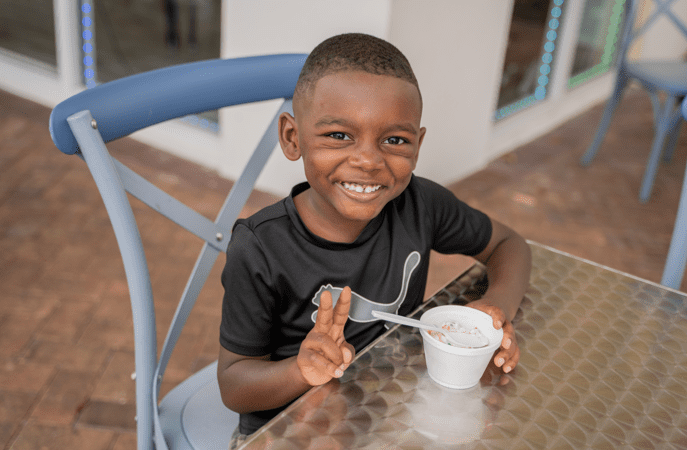 Young boy smiles at camera while enjoying ice cream