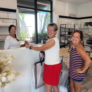 Three women smiling at the checkout counter