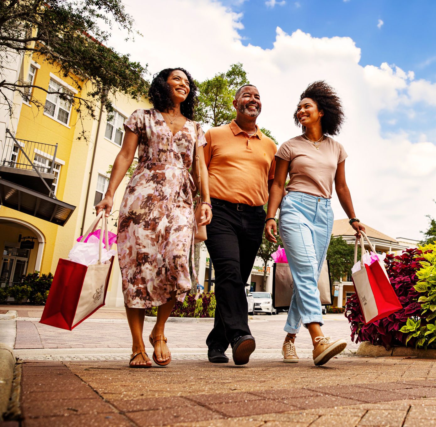 two women and a man walking with shopping bags