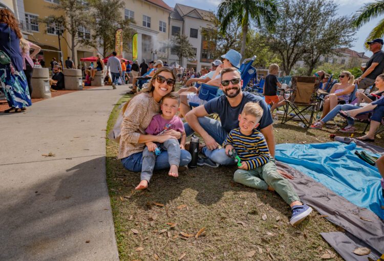 Family of four sitting in the grass at 2023 Taste of Ave event