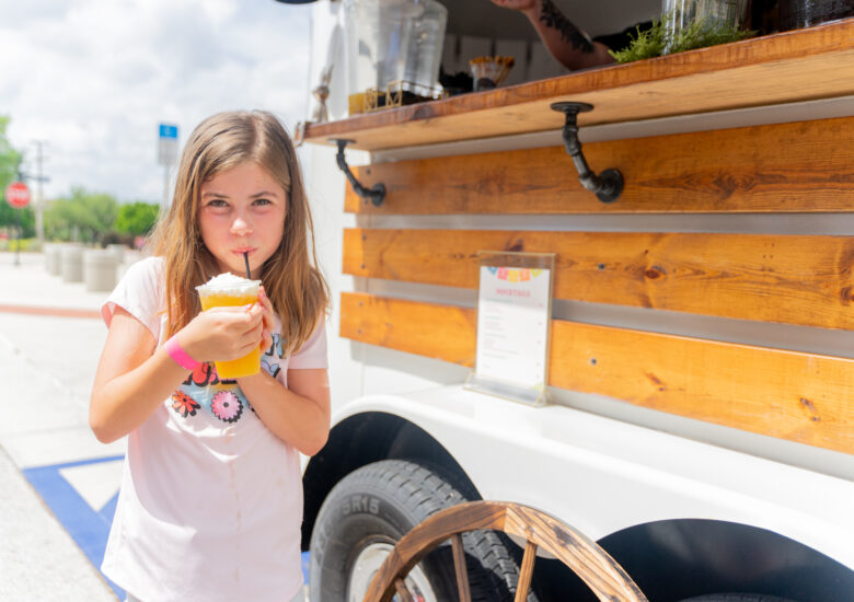 Young girl sips her yummy drink she purchased from a vendor at the 2024 Margarita & Taco Festival