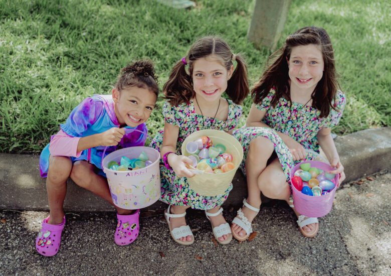 Three friends smile at camera holding their egg baskets