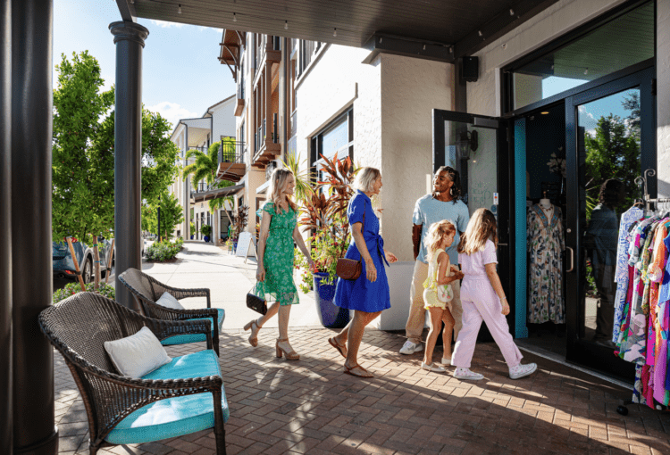 Young man holds the door for family as they enter a store
